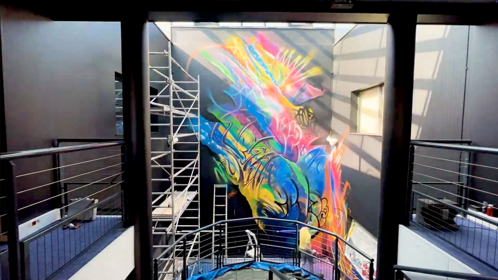 Extrait d'une vidéo de la performance d'Ecloz qui réalise une fresque sur un des murs de la société Trader Services
